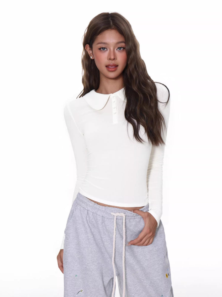 Close-up of a white ribbed knit long-sleeve top with a rounded collar and button details.