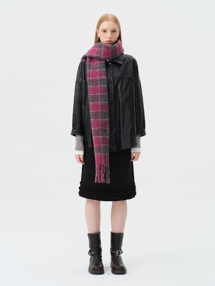 Woman wearing a black leather jacket, black skirt, and a pink and grey plaid scarf.