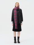 Woman wearing a black leather jacket, black skirt, and a pink and grey plaid scarf.