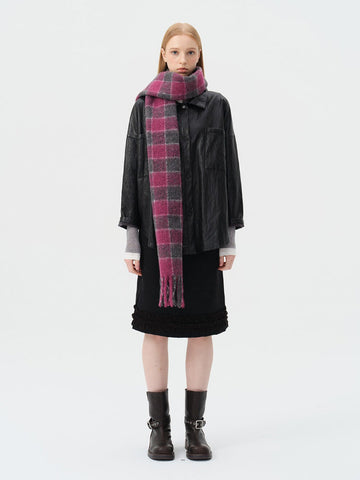 Woman wearing a black leather jacket, black skirt, and a pink and grey plaid scarf.