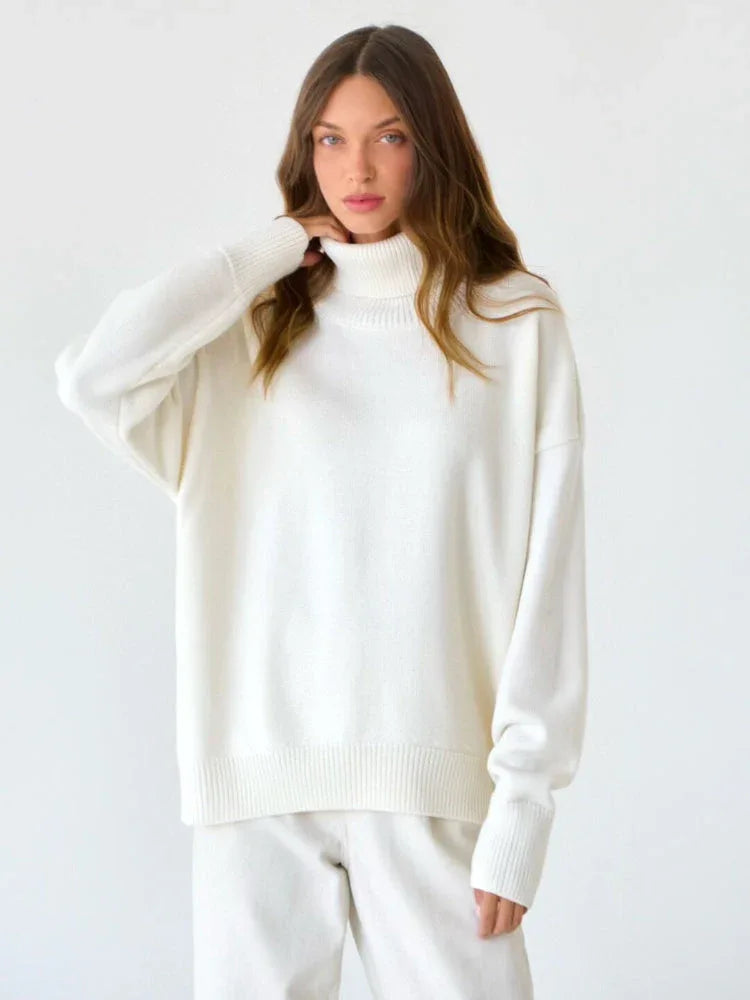 Side view of a woman in a white oversized turtleneck sweater and light wash wide-leg jeans.