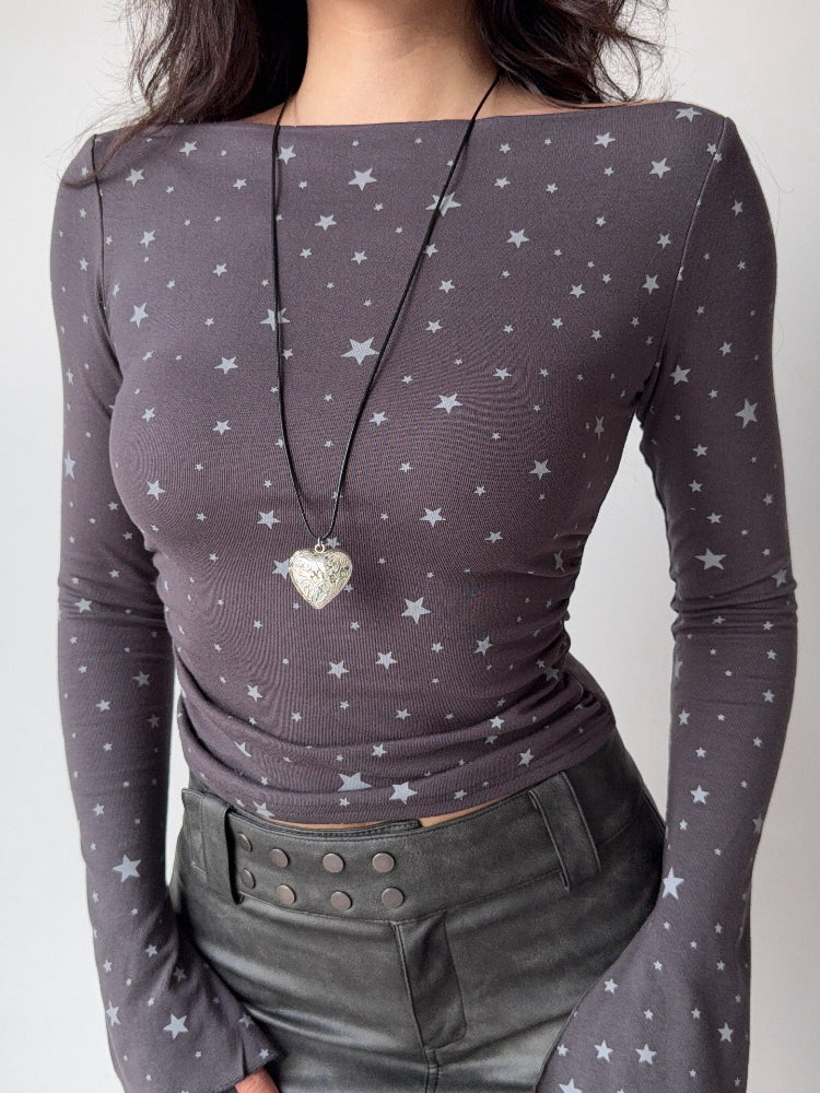 Close-up of a woman's torso in a fitted grey long-sleeve top with a star pattern.