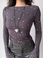 Close-up of a woman's torso in a fitted grey long-sleeve top with a star pattern.