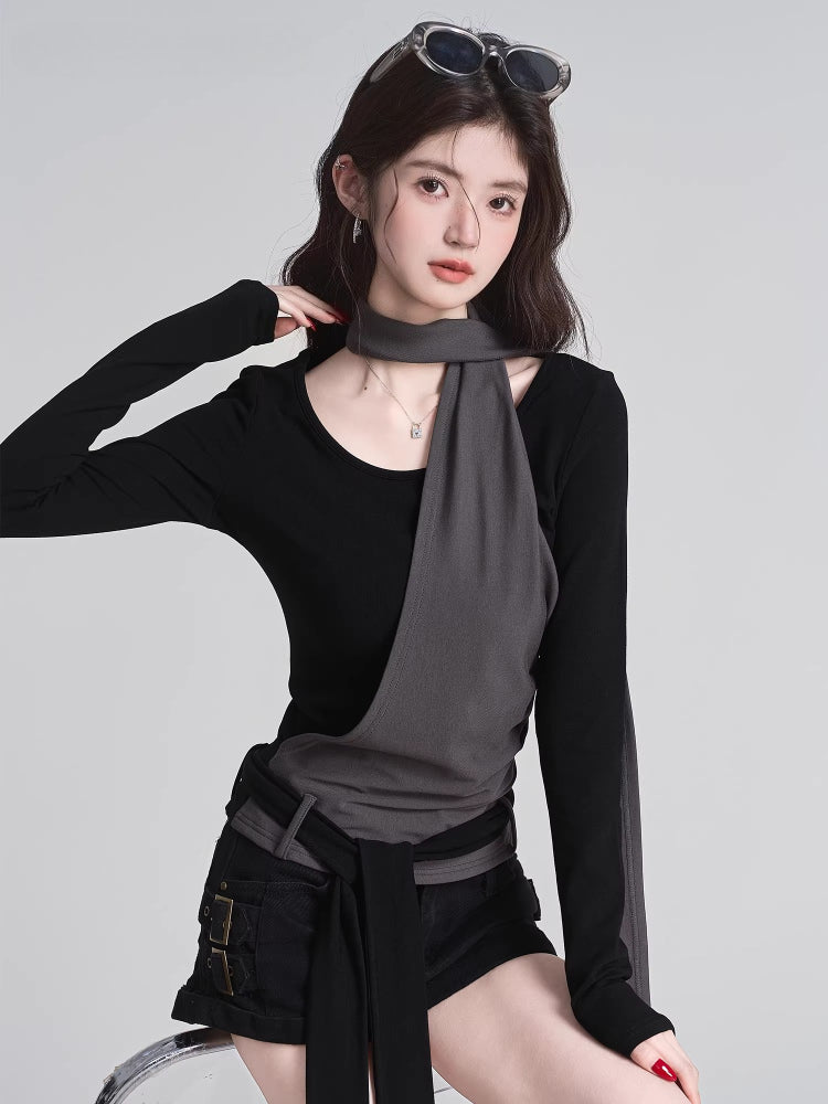 Woman wearing a black long-sleeve top with a grey fabric overlay and integrated scarf