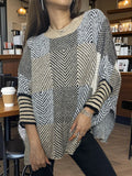 Woman wearing a tan, black, and white geometric print knit poncho with striped cuffs
