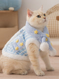 A cat sits wearing a blue and white striped pet vest and scarf set, accented with yellow stars.