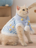 A cat sits wearing a blue and white striped pet vest and scarf set, accented with yellow stars.
