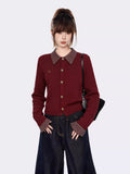 Close-up of the burgundy cable knit cardigan, showing the button details and embroidered emblem.