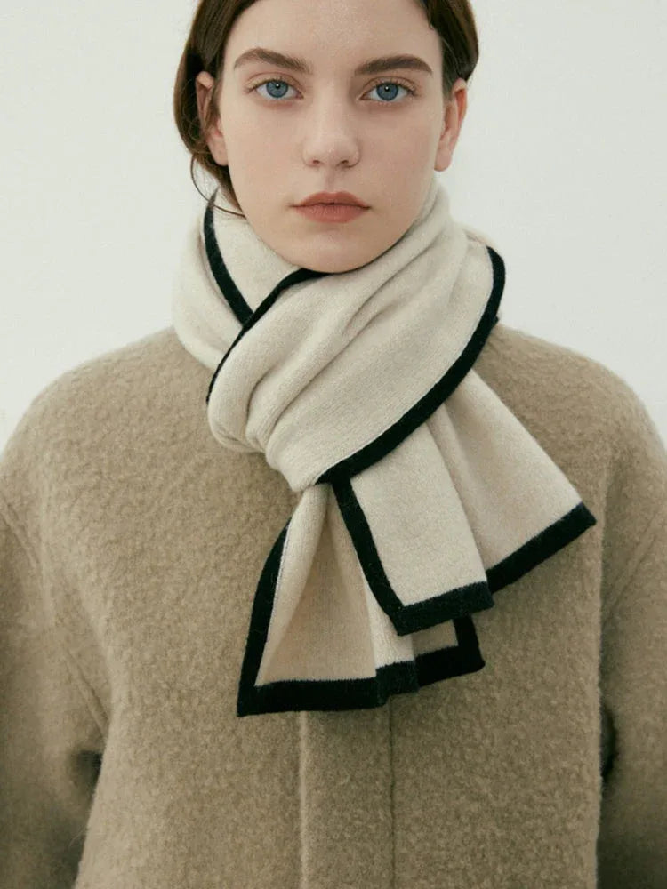 Model wearing a cream knit scarf with black trim around the neck