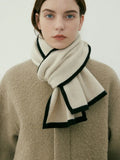 Close-up of a cream knit scarf with black trim