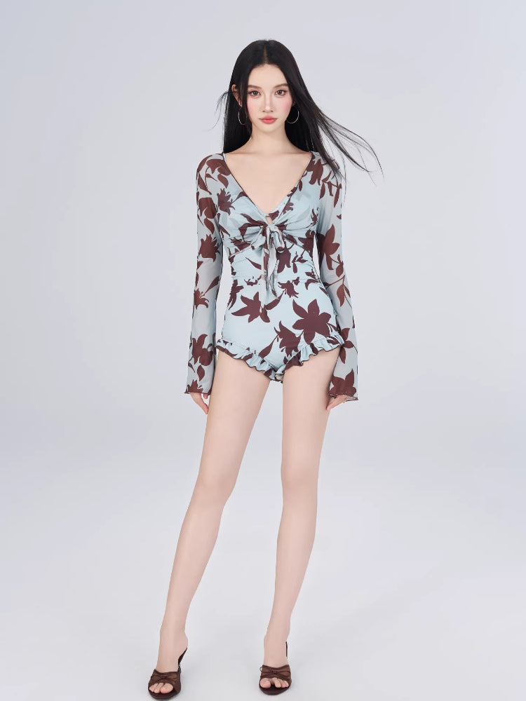 Full body shot of a woman in a floral print romper swimsuit