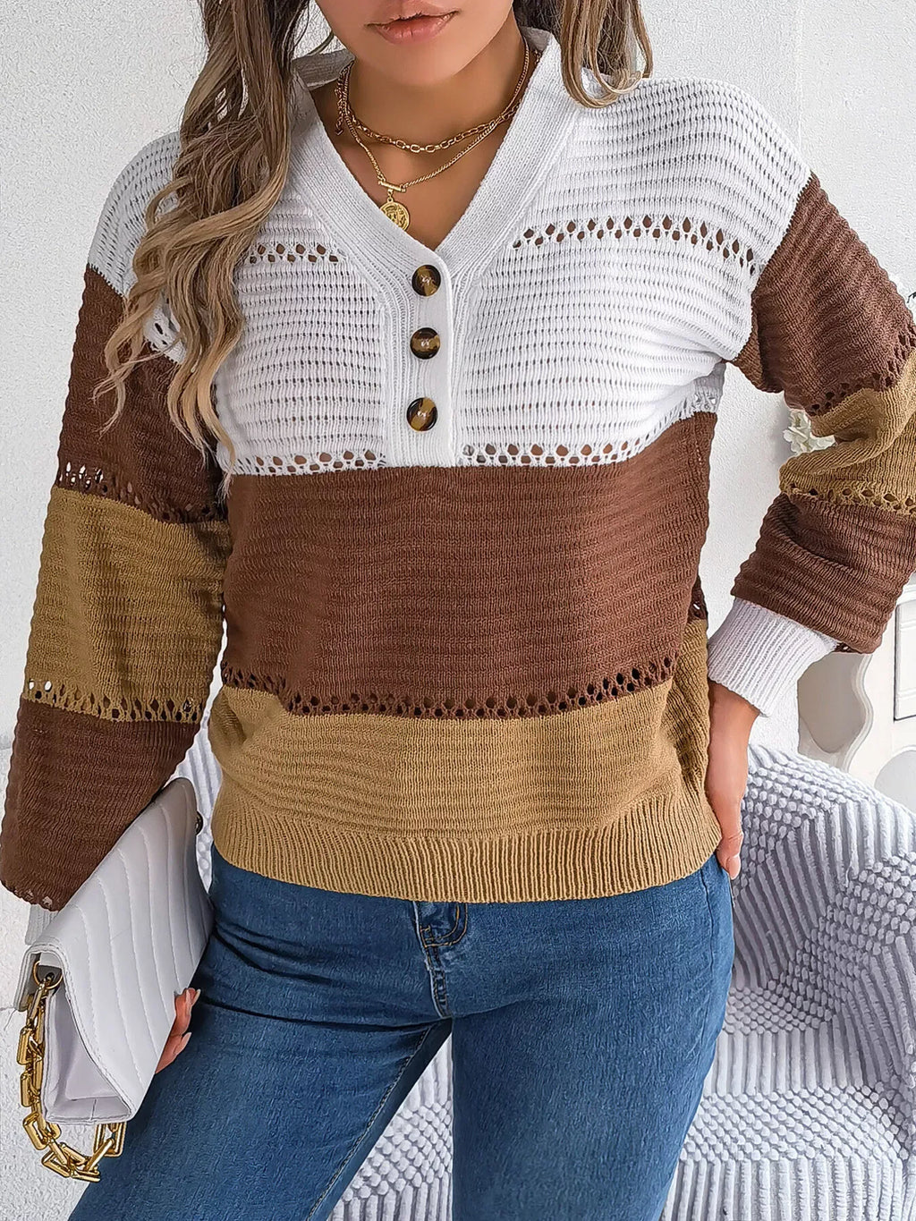 Front view of a woman in a color block knit sweater with a V-neck, button placket, and long sleeves.