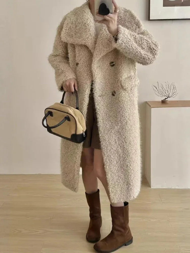 Woman wearing a long cream textured fleece coat with a double-breasted closure and a wide collar.