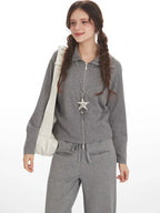 Close-up front view of a woman wearing a grey ribbed knit loungewear set, showing the full zip jacket and drawstring pants.