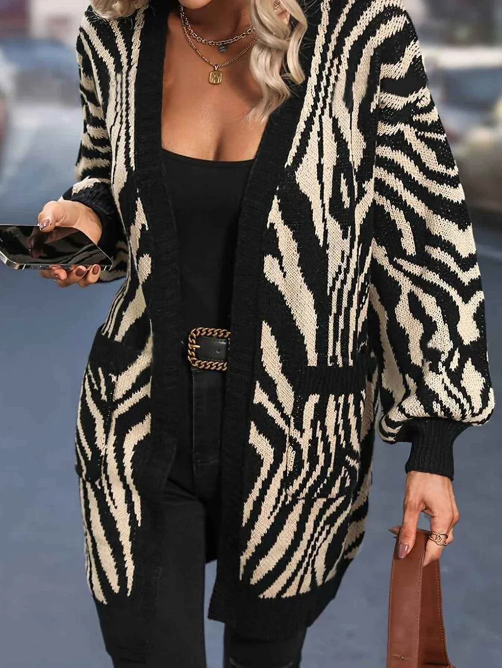 Woman wearing a black and white zebra print long cardigan with pockets and balloon sleeves.