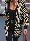 Woman wearing a black and white zebra print long cardigan with pockets and balloon sleeves.