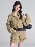 Woman posing with a black shoulder bag, wearing a khaki camp collar shirt dress with long sleeves and a belted waist.