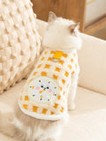 Rear view of a Ragdoll cat wearing a yellow and white checkered fleece pet vest with an embroidered clock graphic