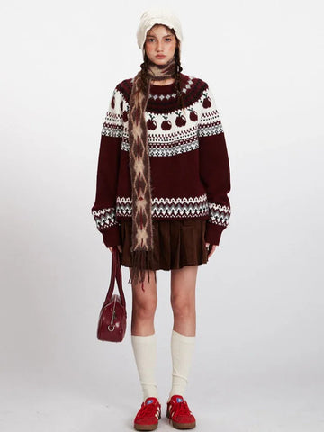 Woman wearing a burgundy Fair Isle crewneck sweater with an apple motif and a white knit hat