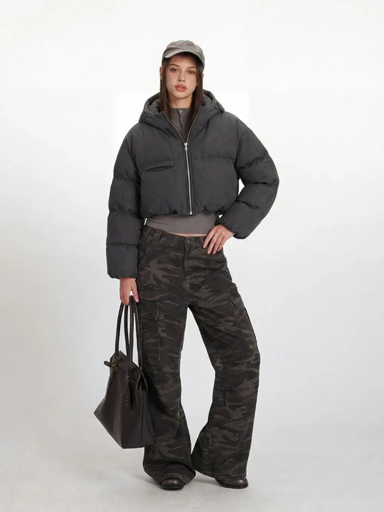 Front view of a woman in a grey cropped puffer jacket with a zippered front and chest pocket.