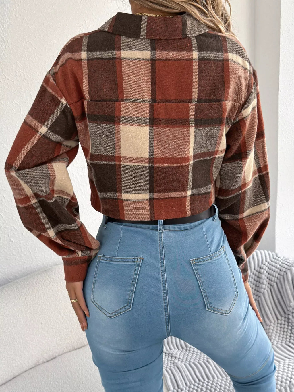 Back view of a woman wearing a plaid cropped shirt jacket and blue jeans