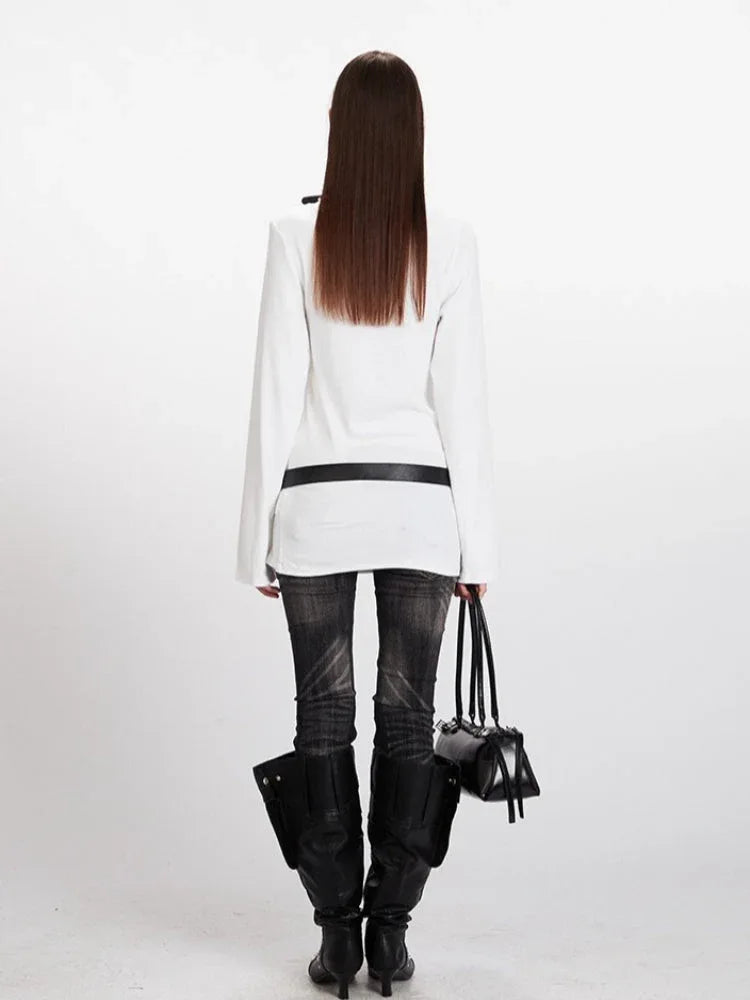 Rear view of a model in a white long-sleeve V-neck top, black belt, and dark wash jeans.