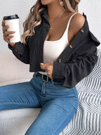 Woman holding a coffee cup while wearing a black cropped corduroy jacket and white tank top