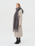 Side view of a woman modeling a long, textured plaid scarf.