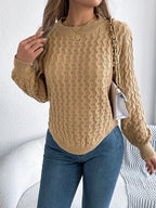 Woman with a white purse slung over her shoulder, wearing a tan textured knit sweater.