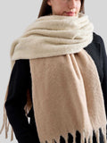 Detail shot of the textured fabric and fringe on a beige scarf