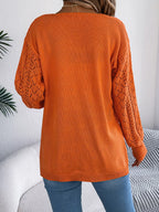 Back view of a woman in an orange open-knit cardigan with long sleeves.