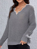 Close-up of the V-neckline of a grey knit sweater with decorative trim.