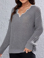 Close-up of the V-neckline of a grey knit sweater with decorative trim.