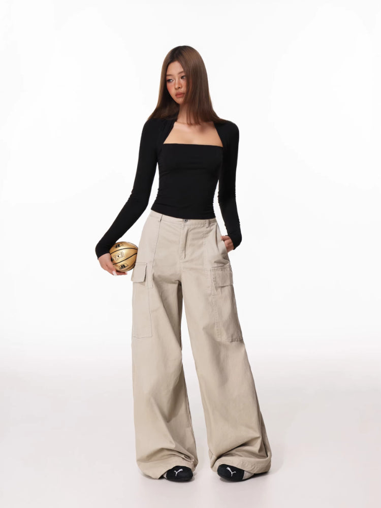 Woman wearing a black long-sleeve square neck top with a draped overlay, paired with beige cargo pants.