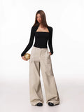 Full body shot of a woman in a black long-sleeve square neck top and beige cargo pants, holding a basketball.
