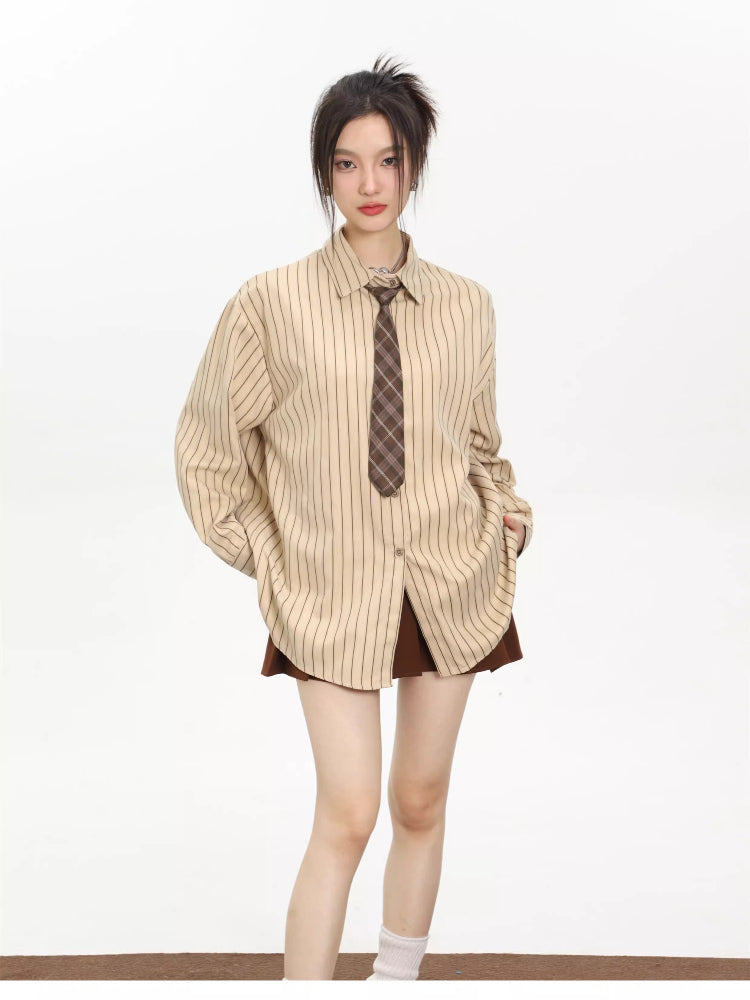 Full body shot of a woman in an oversized beige pinstripe button-down shirt and brown skirt, hands in pockets.