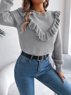Detail of the ribbed hem and cuffs on a gray knit sweater