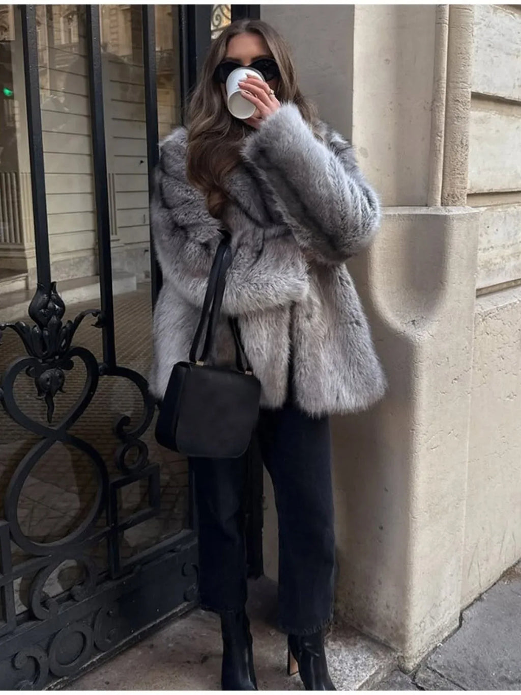 Full body shot of a woman in a grey faux fur coat and black accessories
