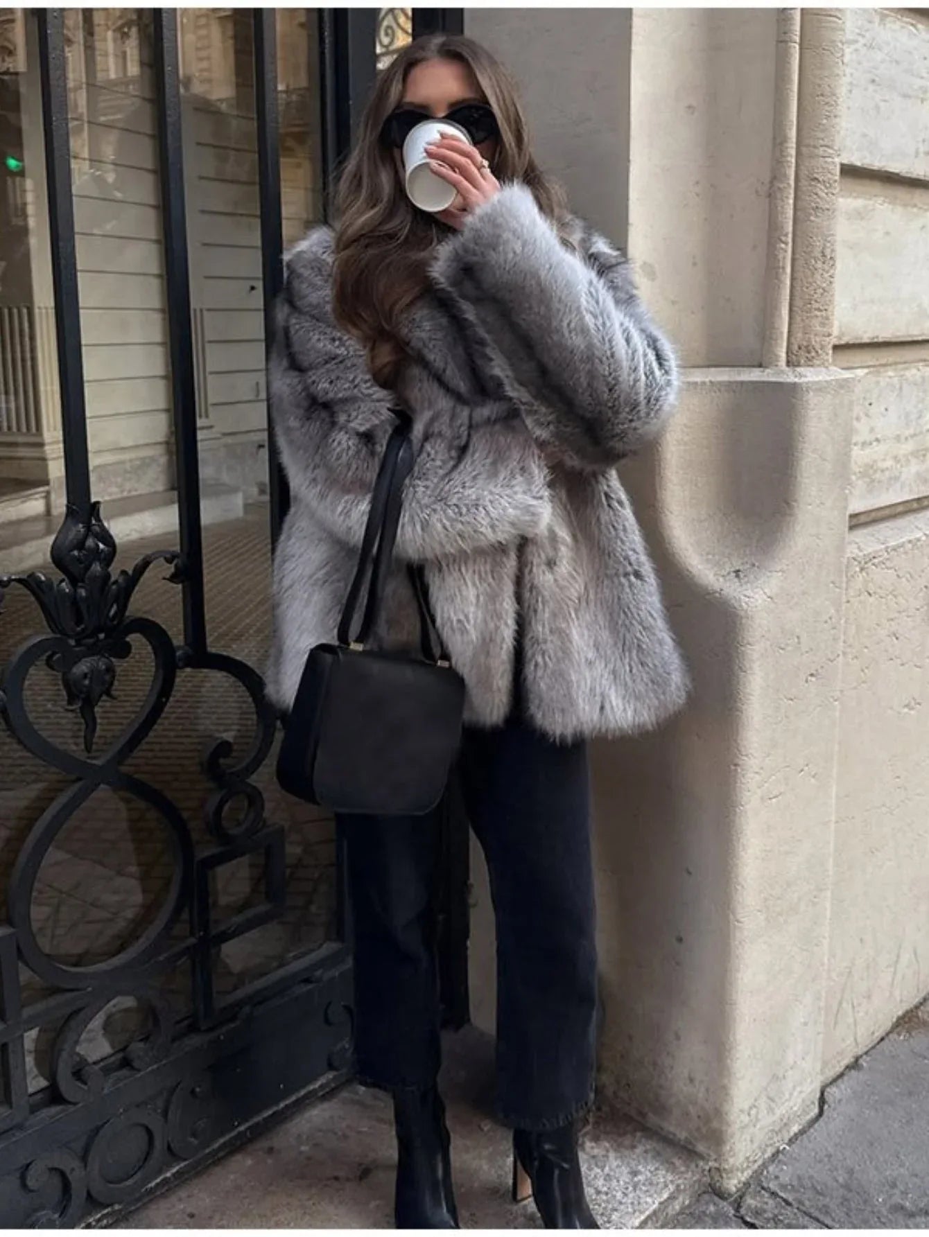 Full body shot of a woman in a grey faux fur coat and black accessories