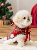 Side view of a white dog wearing a Christmas-themed red plaid pet coat