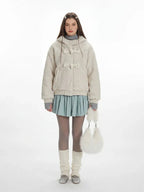 Woman wearing a cream fleece toggle coat with a hood.