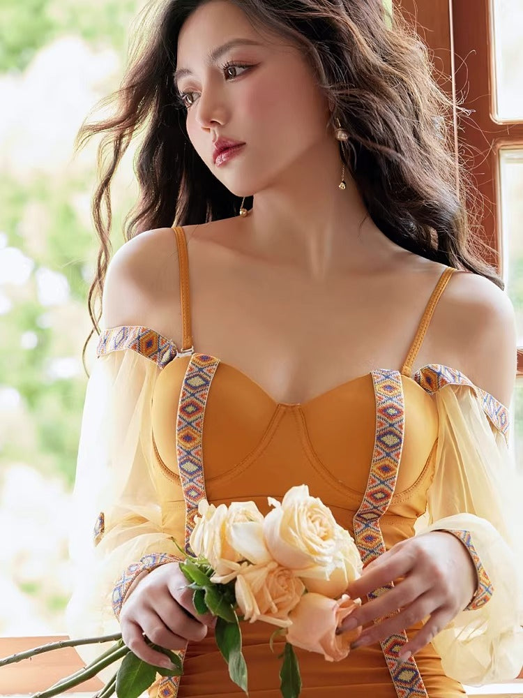 Woman wearing a mustard yellow one-piece swimsuit with sheer bishop sleeves and tribal trim