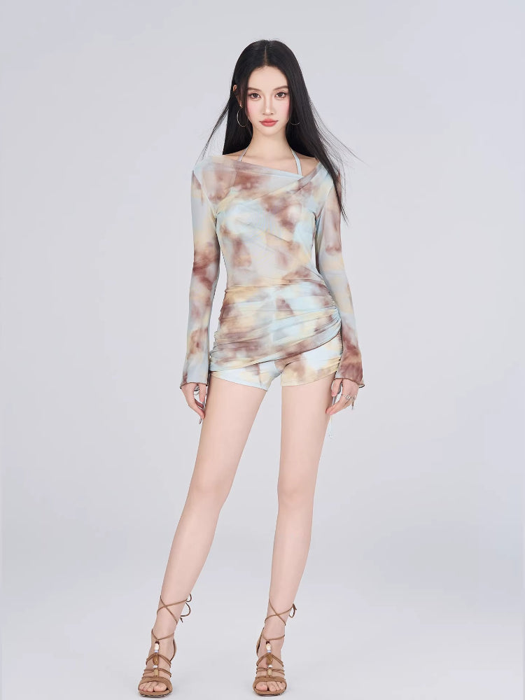 Full-body shot of a woman in a tie-dye mesh top and shorts.