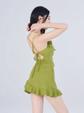 Back view of a woman in a green textured knit mini dress showing adjustable tie straps and ruched sides.
