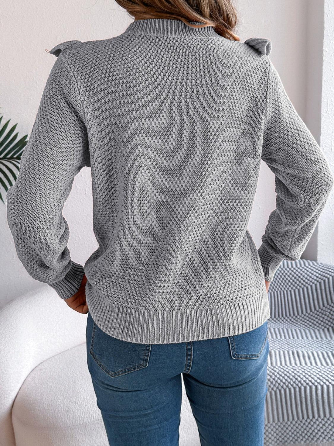 Woman wearing a gray ruffle trim knit sweater