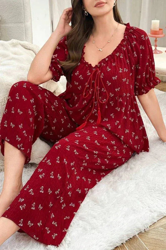 Woman in a red pajama set with a butterfly print, sitting comfortably.