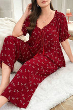 Woman in a red pajama set with a butterfly print, sitting comfortably.