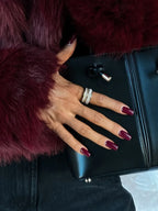 Close-up of a woman's hand wearing rings, showing the texture of a burgundy faux fur jacket.