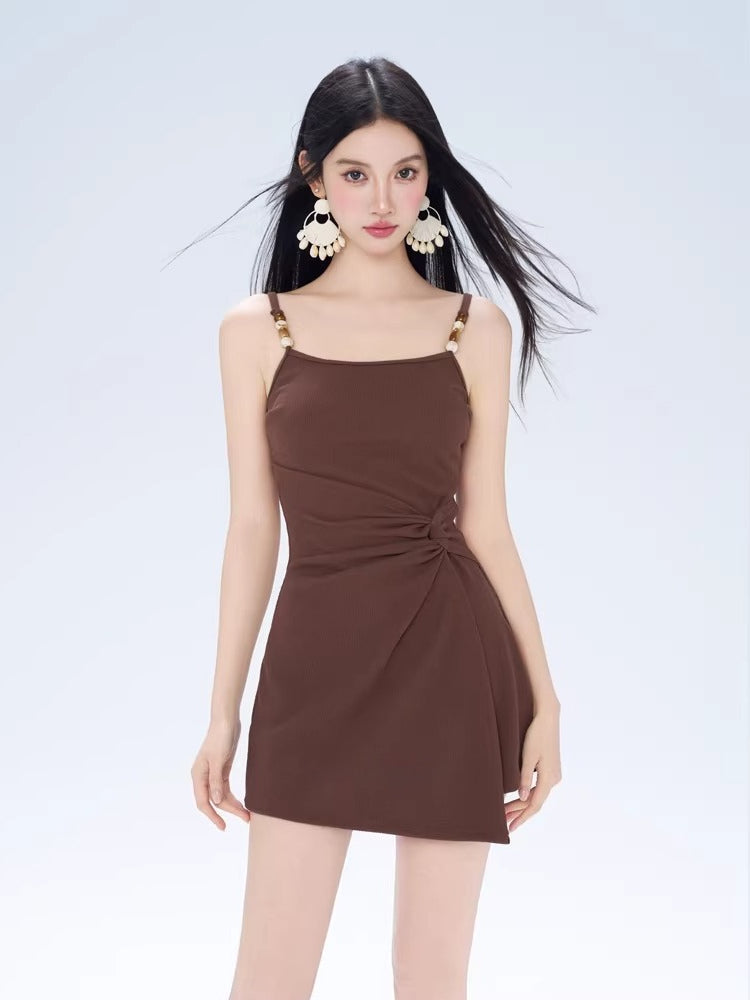 Front view of a woman in a brown ribbed knit mini dress with a knot detail and spaghetti straps.