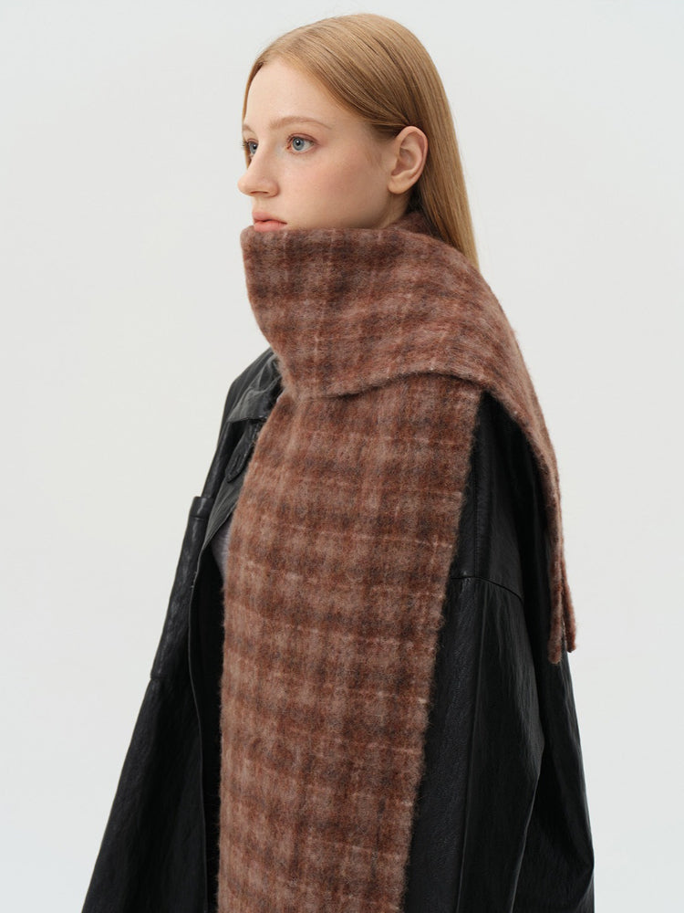 Close-up of a woman's face with a textured brown tartan scarf